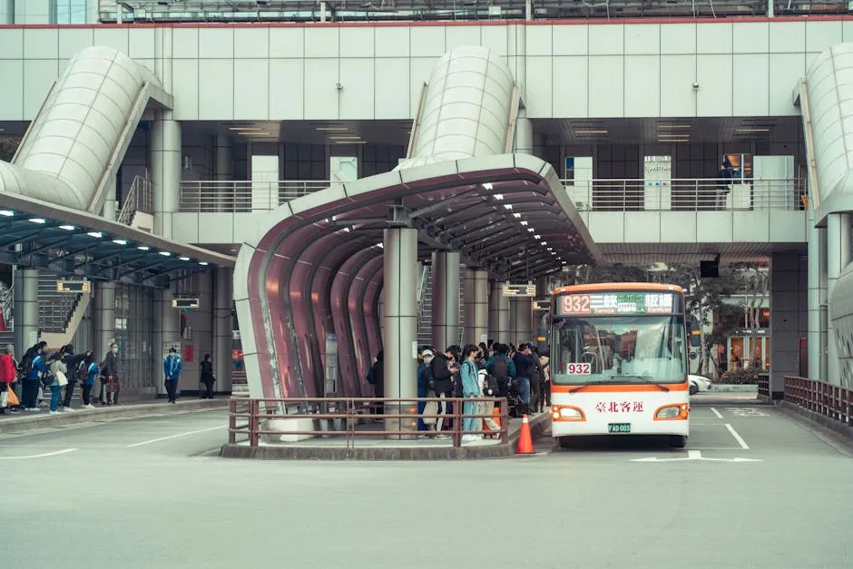 Public transport bus picking up commuters at a modern urban terminal with architectural features.