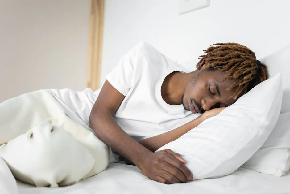 A serene image of a man sleeping peacefully on a white pillow and blanket indoors.