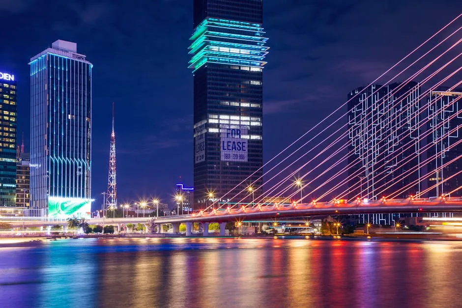 Colorful urban night scene showcasing a brightly lit bridge and modern city skyline reflecting on water.